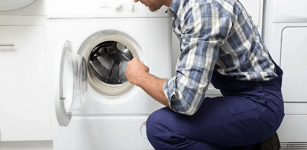 Handyman inspecting a dryer drum and internal parts for repair in Long Beach, CA