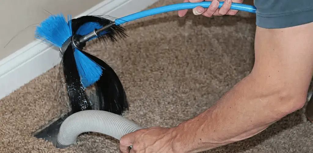 Dryer vent cleaning technician brushing lint from a vent line in Long Beach, CA