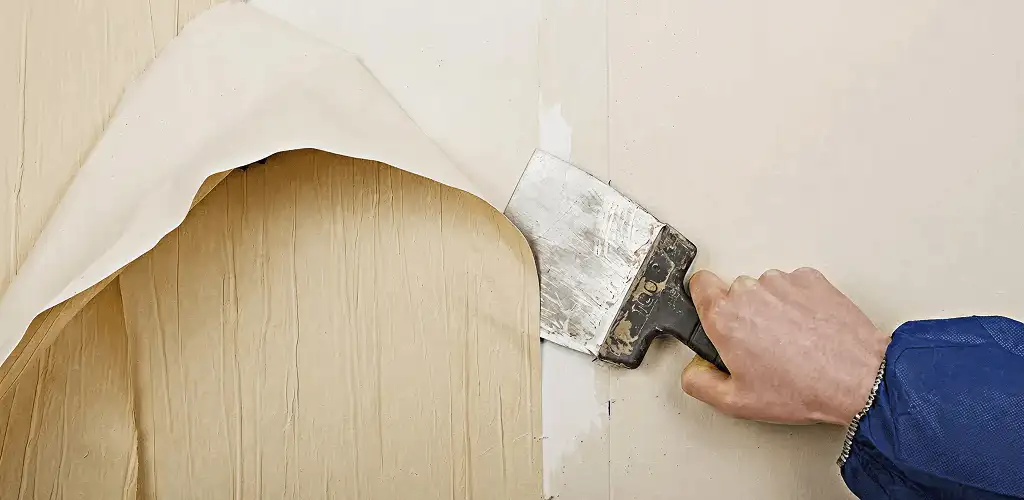Handyman removing wallpaper with a scraper for wall preparation in Long Beach, CA