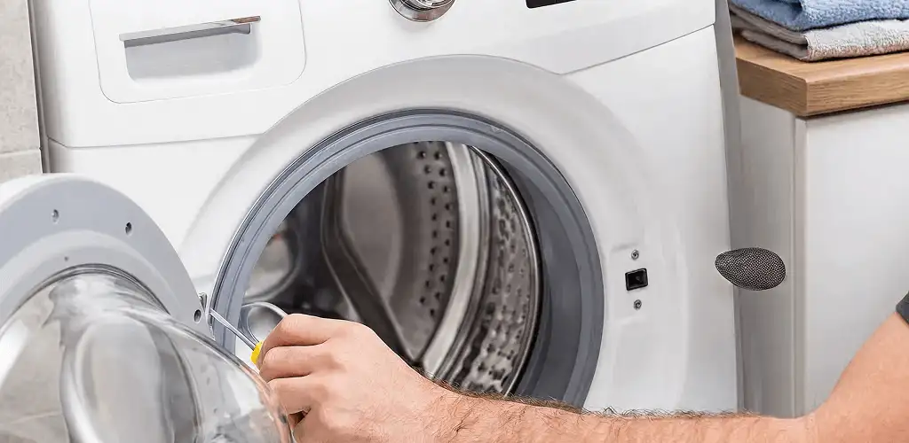 Handyman repairing a front-load washing machine and inspecting the drum in Long Beach, CA
