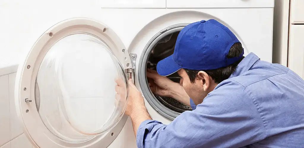 Washing machine repair handyman inspecting a front-load washer drum in Long Beach, CA