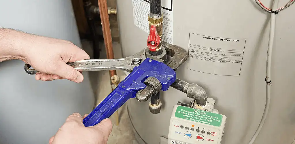 Water heater repair technician tightening the shutoff valve and supply line in Long Beach, CA